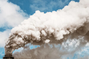 Air pollution: Thick smoke billowing into the sky from a factory chimney.